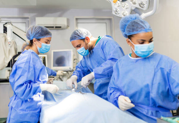 surgeons performing surgery. Doctors are monitoring patient in operating room. They are in hospital.