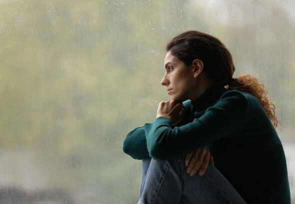 Side view frustrated thoughtful woman looking out rainy window in distance alone, lost in thoughts, upset unhappy young female feeling lonely and depressed, thinking about relationship problems
