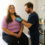 Medical professional listening to patient's breathing, performing routine chest examination in clinical setting, checking health status